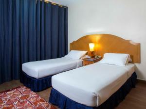 马斯喀特萨费酒店套房的配有黑色窗帘的酒店客房的两张床