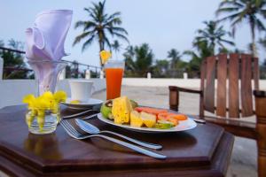 马特勒Savenrose Beach Villa的一张桌子,上面放着一盘水果和一杯饮料