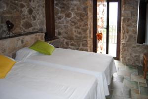 CabezabellosaCasa Rural Romanejo的一间卧室设有两张床和石墙
