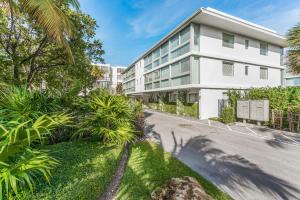 迈阿密Beach Haus Key Biscayne Contemporary Apartments的一条街道前的白色建筑,棕榈树成荫