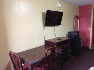 De Leon德莱昂汽车旅馆的客房设有桌子、电视和带椅子的书桌。