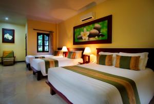 库塔Adi Dharma Hotel Kuta的一间酒店客房,房间内设有三张床