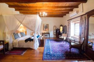 塔尔巴赫Tulbagh Country Guest House - Cape Dutch Quarters的一间卧室配有一张天蓬床和地毯。