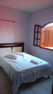 伊塔奥卡Pousada Portal da Ilha的一间卧室配有一张带白色床单的床和一扇窗户。