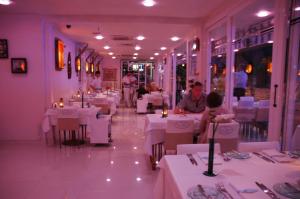 马尔马里斯Devamli Hotel的一间设有白色桌子的餐厅,有人坐在餐厅里