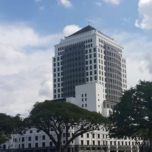 古晋梅德卡宫套房酒店的一座高大的白色建筑,前面有树木