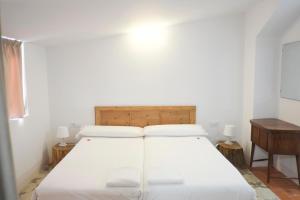 塔拉戈纳皮加尔酒店的配有木制床头板的客房内的白色床