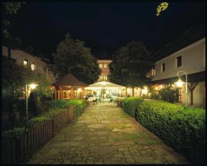 SierningLandhotel Forsthof的一条鹅卵石人行道,通往晚上的房子