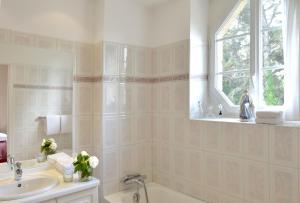 圣库隆Hostellerie de la Motte jean的带浴缸、水槽和窗户的浴室