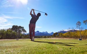 东冰川公园冰川公园旅馆的人在田野上挥舞高尔夫球杆