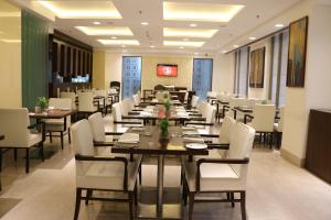Bhiwadi比瓦迪江山丽怡酒店的大型用餐室配有桌子和白色椅子