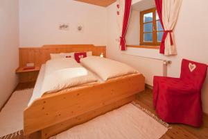帕特加森Hof Wieser的一间卧室配有木床和红色椅子