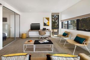 悉尼奎斯特麦格理公园公寓的客厅配有沙发、椅子和电视