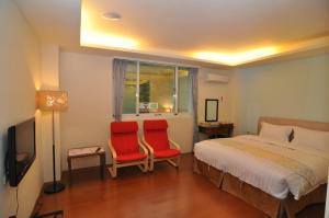 Wenquan橙品温泉民宿的一间卧室配有两张红色椅子和一张床