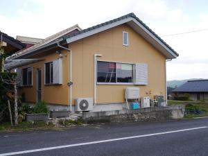 恵那市富田旅馆的街上有两台空调的黄色房子