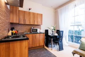 伦敦艾丽西亚南肯辛顿公寓的厨房配有木制橱柜和带微波炉的桌子。