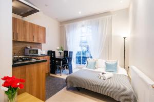 伦敦艾丽西亚南肯辛顿公寓的一间卧室配有一张床,厨房配有窗户