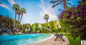 曼杜里亚瑞莱斯雷加多米兹亚酒店的棕榈树游泳池旁的长凳