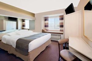 乔普林温德姆·乔普林麦克罗特客栈&套房的酒店客房设有一张大床和一张书桌。