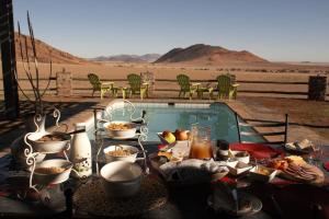 马尔塔赫厄Greenfire Desert Lodge的游泳池旁带食物的桌子