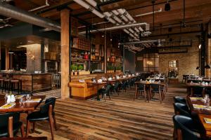 明尼阿波利斯Hewing Hotel的餐厅铺有木地板,配有桌椅