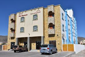 Al ‘AqarGreen Mountain Hotel Apartments的两辆车停在停车场的大楼