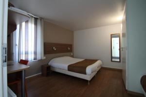 尚布雷莱图尔南图尔法斯特酒店的一间卧室配有一张床、一张书桌和一个窗户。