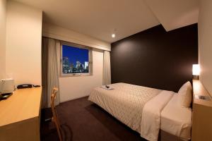 东京日本亚洲会馆酒店 的一间卧室配有一张床、一张书桌和一个窗户。