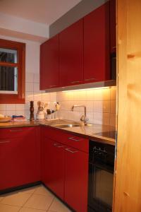 埃尔嫩Chalet Bettlihorn的一间带红色橱柜和水槽的厨房
