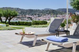 斯科派洛斯Skopelos Village Hotel的庭院设有两把躺椅和一张桌子