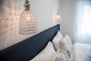 梅拉诺M-Loft merangardenvilla的挂在床上的吊灯和白色枕头