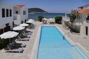 斯科派洛斯Skopelos Village Hotel的一个带椅子和遮阳伞的游泳池以及大海