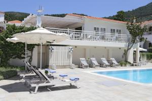 斯科派洛斯Skopelos Village Hotel的房屋旁的游泳池配有椅子和遮阳伞