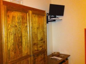 乌斯蒂卡Hotel Giulia的一间设有木门的房间和墙上的电视