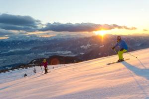 特雷芬Landhaus Gailer的两人在日落时分在雪覆盖的斜坡上滑雪