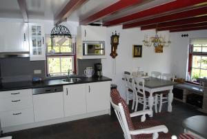 JistrumVakantiehuis "It koaihûs"的厨房配有白色橱柜和桌椅