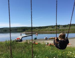 NorråkerBo på Lanthandel的坐在湖边秋千上的女人