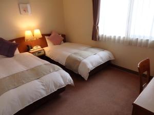 IshiokaHotel Hashimotorou的酒店客房设有两张床和窗户。