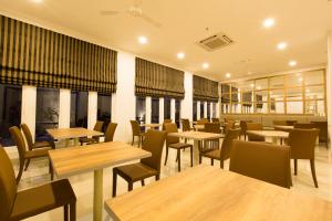 苏加武眉Sparks Odeon Sukabumi, ARTOTEL Curated的餐厅设有木桌、椅子和窗户。