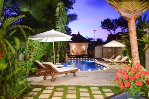 Tirtagangga提塔阿玉酒店及餐厅的后院设有带椅子和遮阳伞的游泳池