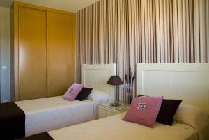 波多诺伏APARTAMENTOS DE CANELAS SUITES con AMPLIAS TERRAZAS的酒店的客房 - 带2张带粉红色枕头的床