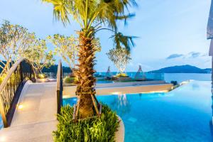 芭东海滩Crest Resort & Pool Villas - SHA Extra Plus的水边的游泳池,棕榈树
