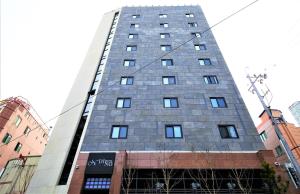 釜山釜山站迪诺酒店 的一座高大的灰色建筑,窗户在城市里