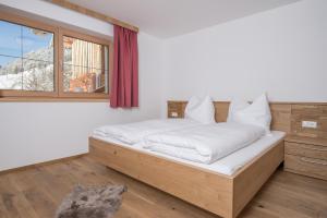 阿尔卑巴赫Ferienwohnungen H&P的一间卧室配有一张带白色床单的床和一扇窗户。