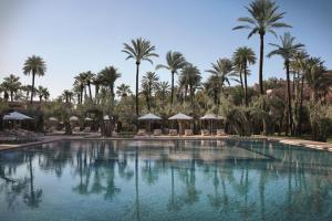 马拉喀什皇家曼苏尔马​​拉喀什酒店的一座棕榈树和遮阳伞的大型游泳池