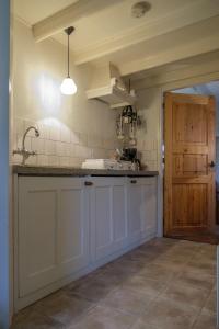 ZweelooOes-Tilber的厨房配有白色橱柜、水槽和门