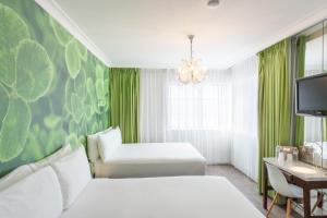 迈阿密海滩总统大酒店的一间卧室设有两张白色的床和绿色的墙壁