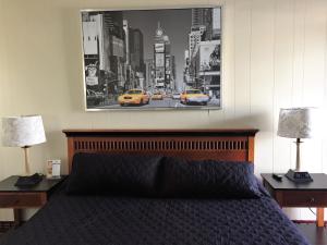 劳德代尔堡Vacation Inn Motel - Fort Lauderdale Airport的一间卧室配有一张带两盏灯的床,墙上挂着一张照片