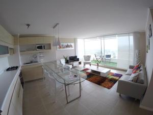 阿尔加罗沃Departamento Vista al Mar, Laguna Bahia, Algarrobo 1205H的厨房以及带玻璃桌的起居室。