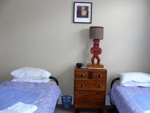 奥玛鲁奥马璐粉红色度假屋的一间卧室配有两张床和一个带台灯的梳妆台